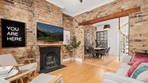 Ein Wohnzimmer mit Kamin, einem an der Wand montierten Fernseher und einem Essbereich mit Tisch und Stühlen.