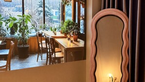 Comedor con mesa y sillas de madera, plantas en macetas y vistas a un paisaje nevado a través de amplios ventanales.