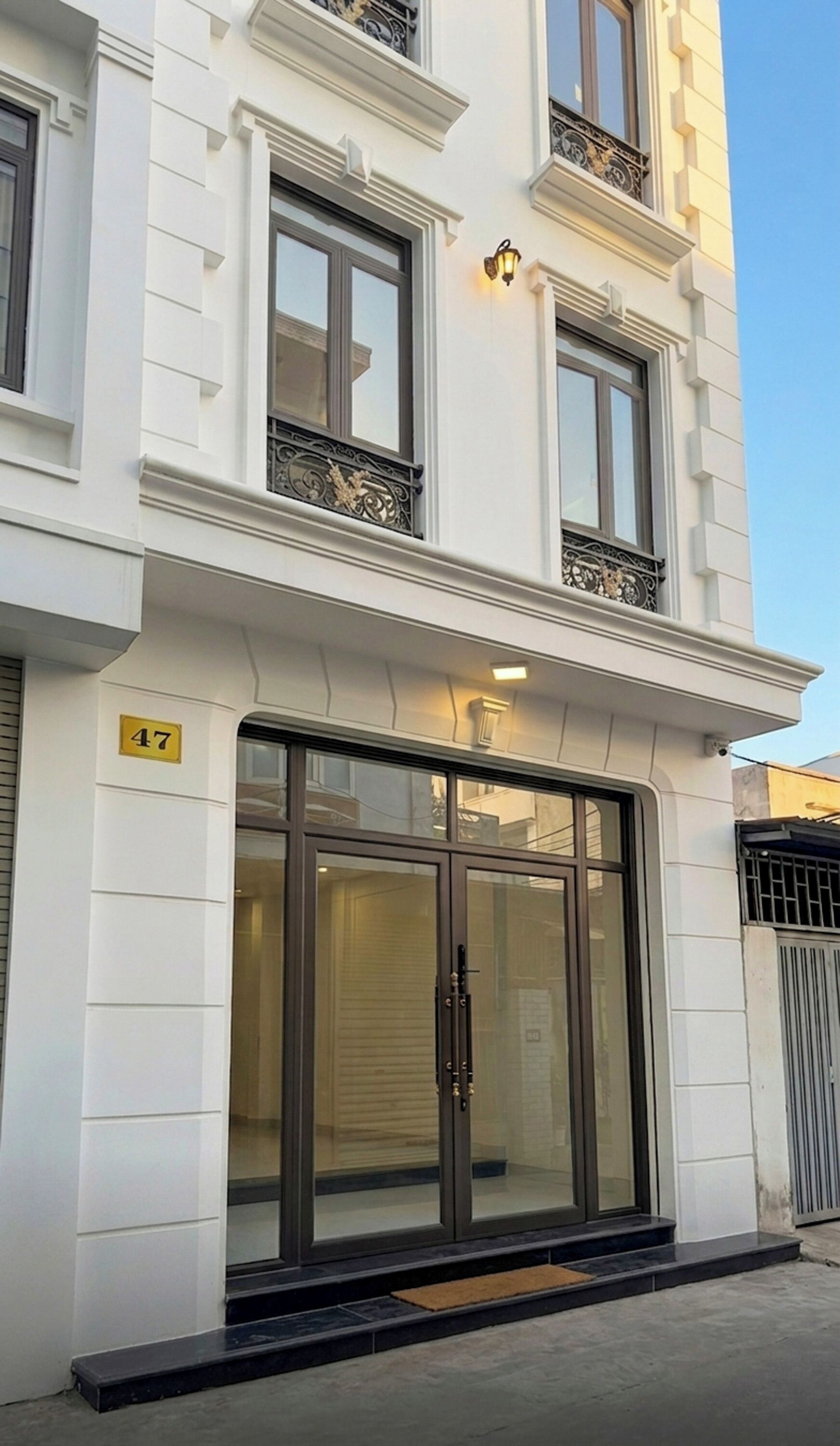 Un bâtiment doté d’une grande entrée en verre, d’une enseigne portant le numéro « 47 » et d’un balcon orné de balustrades décoratives.
