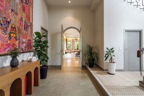 A hallway with a large colorful tapestry, potted plants, and a modern interior.