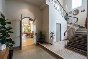 Un interior amplio con una escalera, un comedor y vista a otra habitación.
