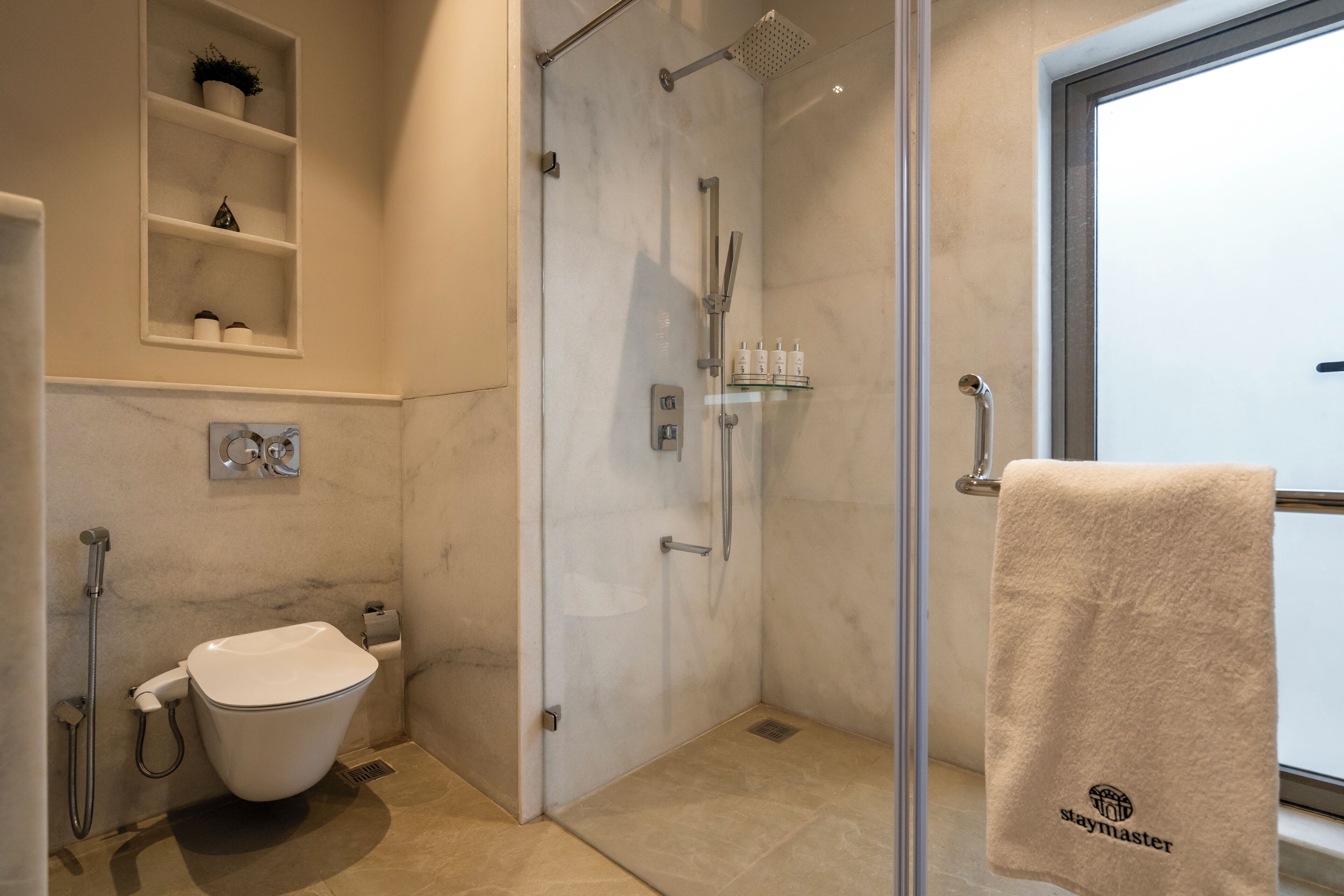 A modern bathroom with a glass-enclosed shower, a toilet, and a sink.