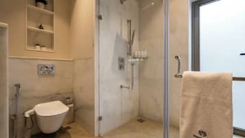 A modern bathroom with a glass-enclosed shower, a toilet, and a sink.