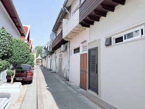 A narrow street with buildings on both sides, a parked car, and a tree. - Entire Building , Shophouse in Old Town Bangkok (Bangkok)