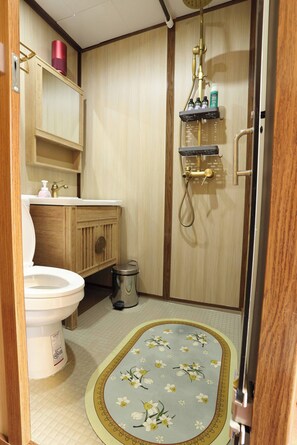 A bathroom with a toilet, sink, and shower. There is a trash can and a shelf with toiletries. - Entire Building , Shophouse in Old Town Bangkok (Bangkok)