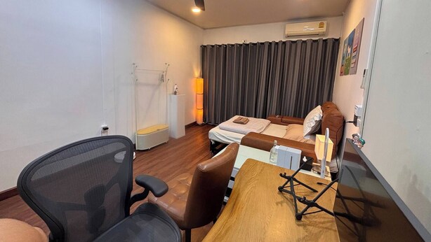 Ein Hotelzimmer mit einem Bett, einem Schreibtisch, einem Sessel, einem Deckenventilator und einer Klimaanlage.