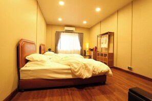 A hotel room with a large bed, a bedside table, a lamp, a wardrobe, and an air conditioning unit. - Entire Building , Shophouse in Old Town Bangkok (Bangkok)