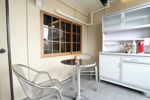 A compact kitchen with a window, a dining table with chairs, and a refrigerator. - Entire Building , Shophouse in Old Town Bangkok (Bangkok)