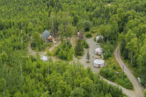 Uma área arborizada com uma casa e duas yurts.