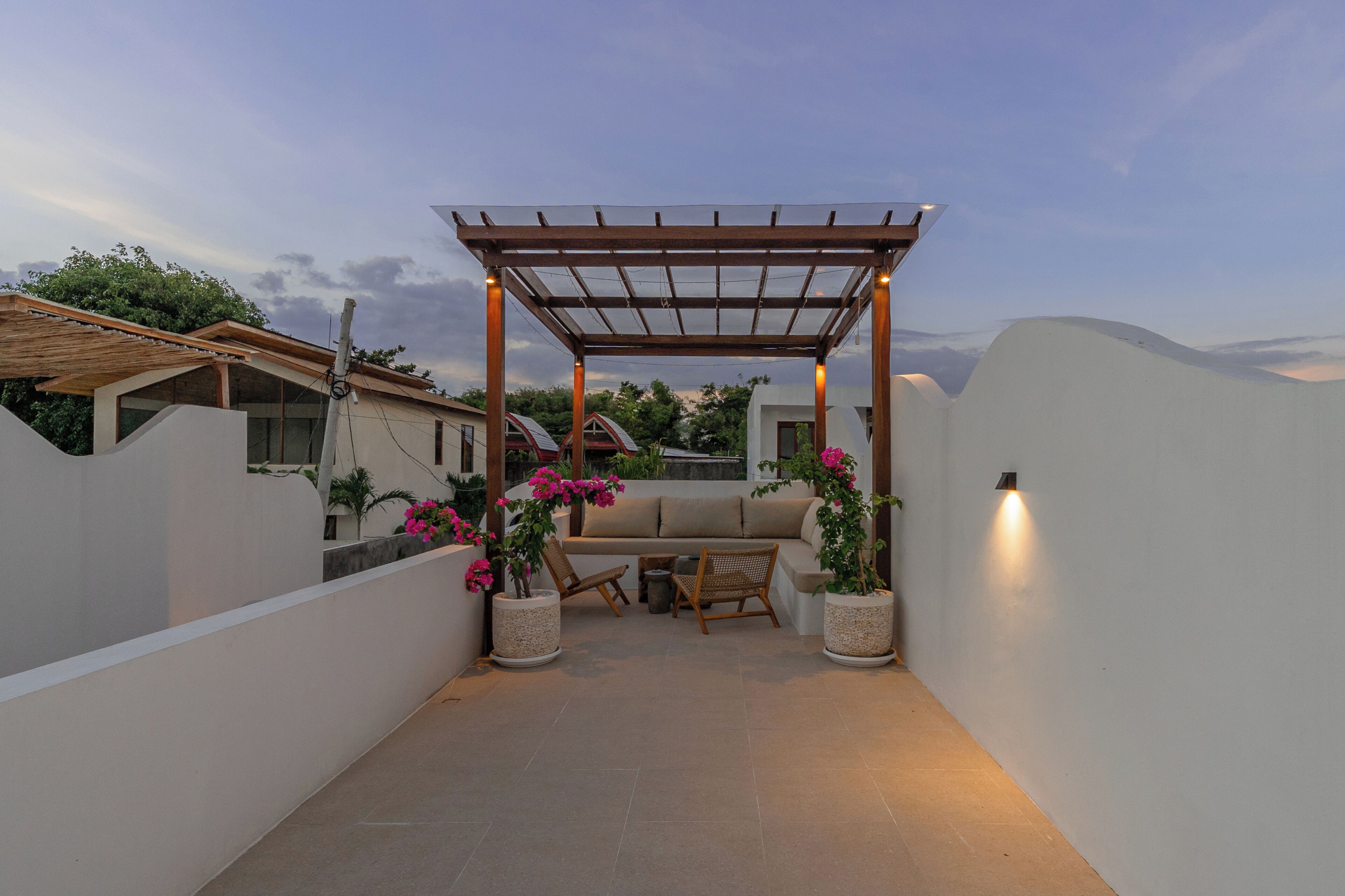 Un patio cubierto con pérgola, asientos y plantas en macetas.