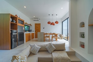 Eine moderne Küche mit Einbauofen, Kühlschrank und Mikrowelle. Ein Essbereich mit Holztisch und Stühlen ist ebenfalls vorhanden.