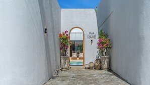 A narrow alleyway leading to a villa entrance with a pool, potted plants, and outdoor furniture. - Villa Rame (Uluwatu)