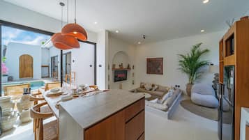Una cocina moderna con comedor, una sala de estar con sofá y vistas al exterior.