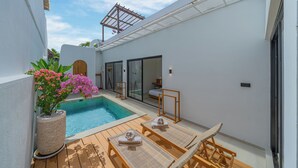 A modern outdoor pool area with a wooden deck, lounge chairs, and a potted plant. - Villa Rame (Uluwatu)