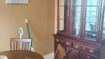 A dining area with a round table, chairs, a cabinet with glass doors, and a wall-mounted artwork.