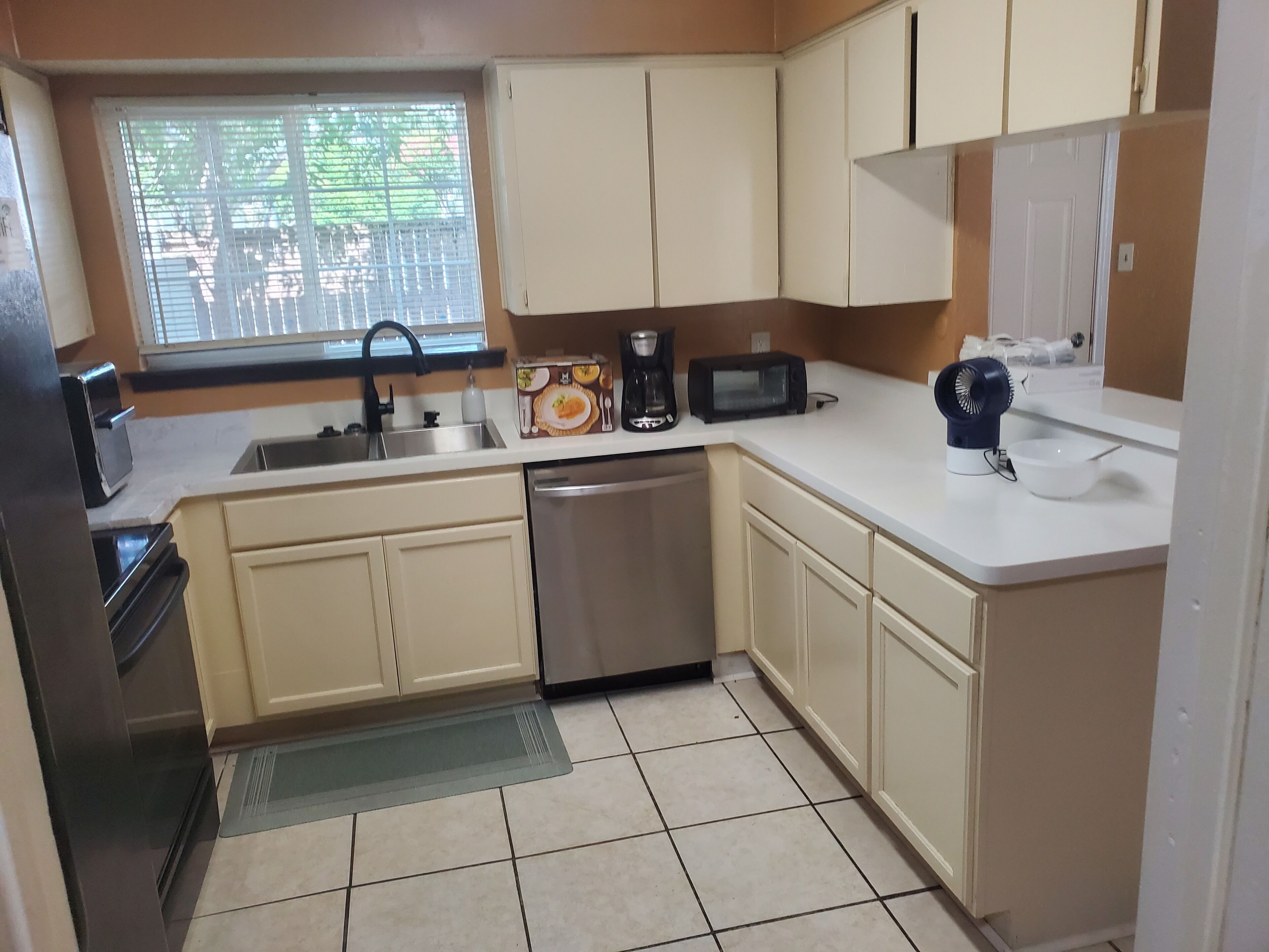 A compact kitchen with a dishwasher, a coffee maker, a microwave, and a sink.