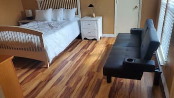 A bedroom with a bed, bedside table, lamp, and a sofa.