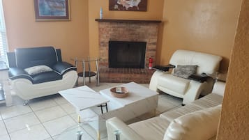 A living room with a fireplace, two sofas, a coffee table, and a small side table.