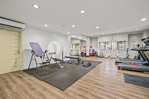 A gym with exercise equipment, a treadmill, and a mirror. - Nevora by Kozystay - Kuningan (Jakarta Selatan)