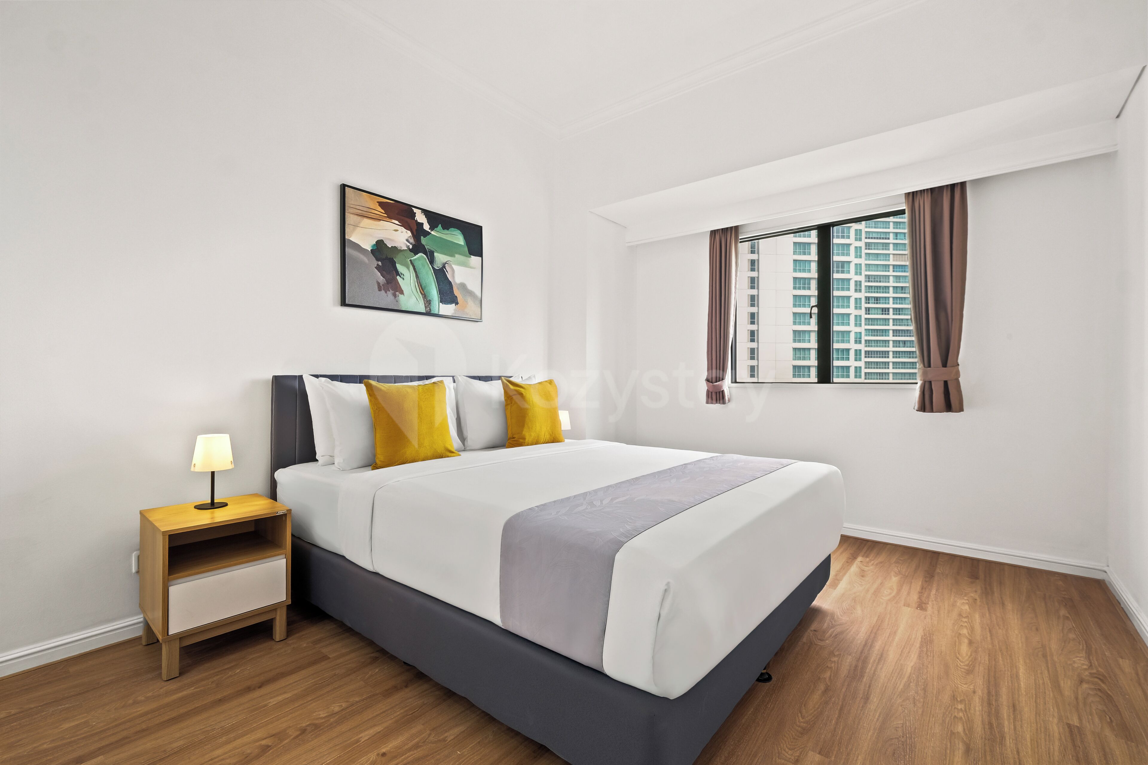 A modern bedroom with a bed, a nightstand, a lamp, a window with curtains, and a painting on the wall.