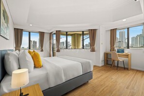 A modern hotel room with a large bed, a desk, and a view of the cityscape. - Nevora by Kozystay - Kuningan (Jakarta Selatan)