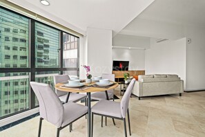 A modern living room with a dining area, large windows, and a sofa. - Nevora by Kozystay - Kuningan (Jakarta Selatan)