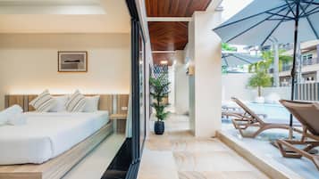 A modern hotel room with a bed, a potted plant, and a view of the pool area.