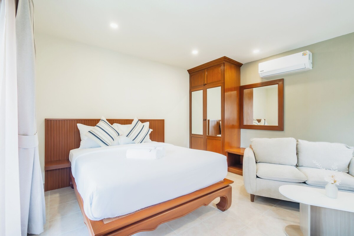 Une chambre d’hôtel comprenant un lit, une armoire, un canapé, une petite table et un appareil de climatisation.