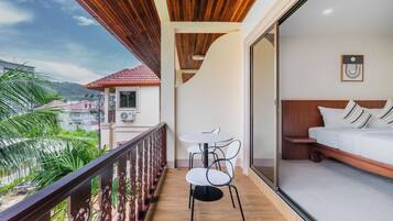 A balcony with a wooden ceiling, a small table with chairs, and a bed with pillows.