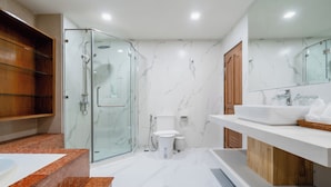 Un baño moderno con cabina de ducha de vidrio, inodoro y tocador con lavamanos y espejo.