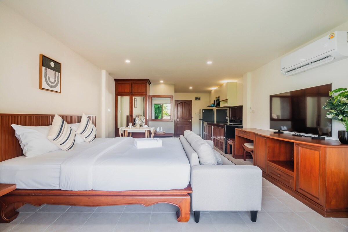 Une chambre d’hôtel avec un grand lit, une télévision, un bureau et une kitchenette.