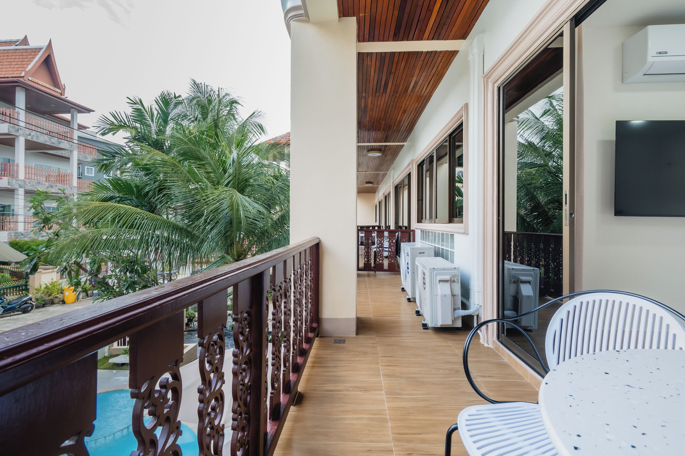 A balcony with a wooden railing, a white chair, and air conditioning units.