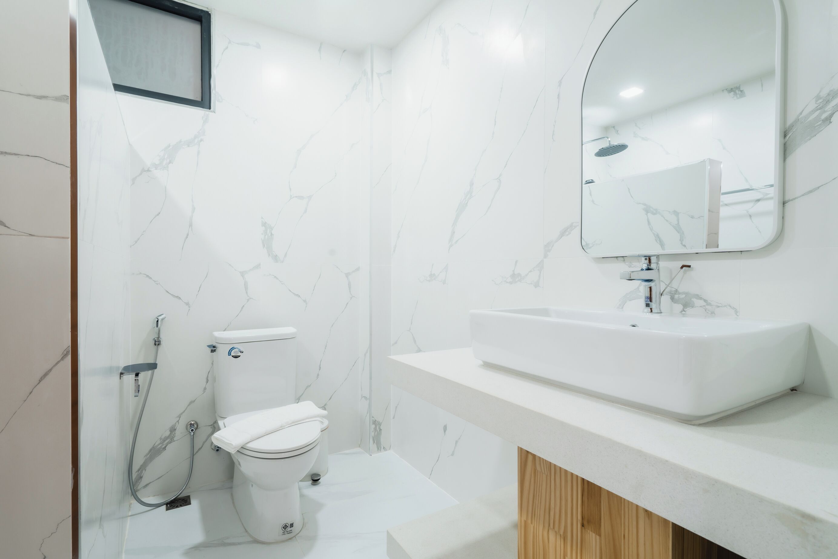 Et moderne badeværelse med toilet, bidet og et vaskemøbel med spejl.