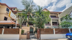 Un edificio residencial con entrada porticada, varios balcones y un cartel que indica un lugar.