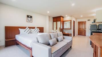 Habitación de hotel con cama, sofá, una mesita, espejo y kitchenette.