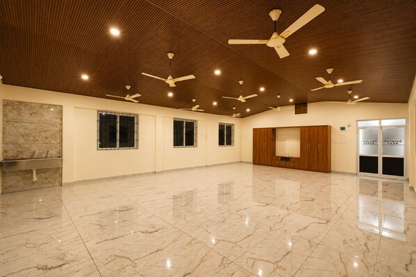 A spacious room with a marble floor, ceiling fans, and a wooden wardrobe.