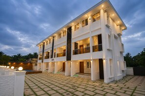 A multi-story building with a flat roof, large windows, and a paved courtyard.