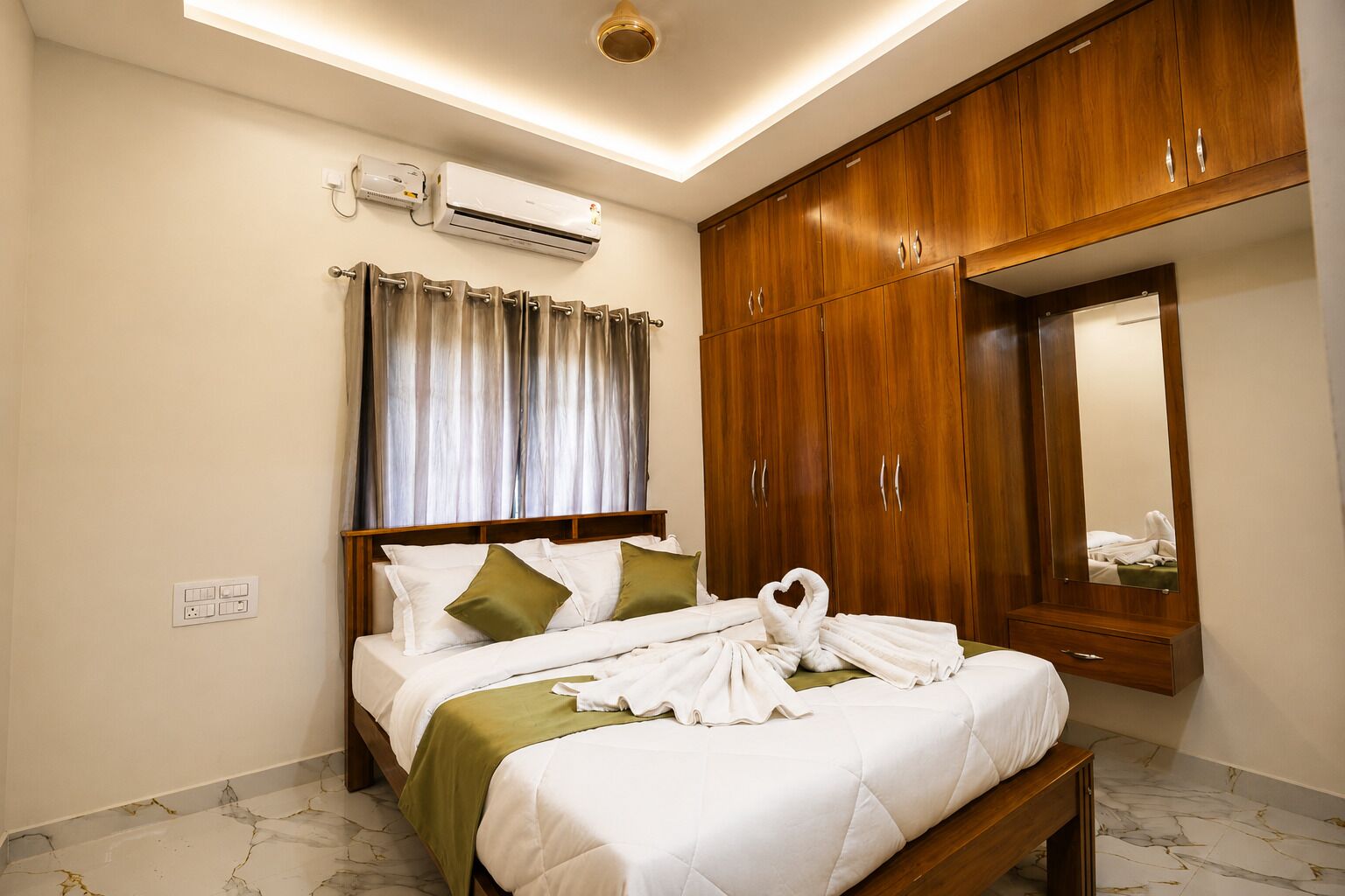 Quarto de hotel com cama, espelho, guarda-roupa de madeira e aparelho de ar condicionado.