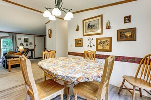 Ein Esszimmer mit einem runden Tisch, Holzstühlen und einer Tischdecke mit Muster.