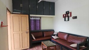 Una habitación con sofá, mesa de madera, ventilador de techo y armario.