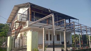 Una casa de dos pisos con un balcón y un espacio exterior cubierto.