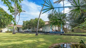 A courtyard with a small pond, palm trees, and a building with a tiled roof.