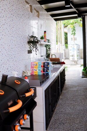 A counter with a white speckled backsplash, a plant, and various items including a water dispenser and a box of tissues.