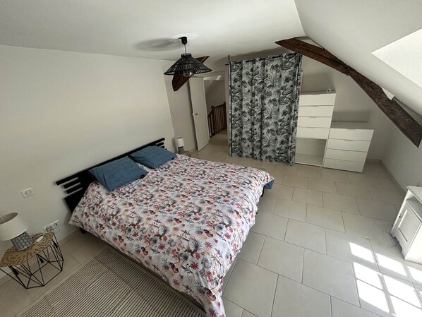 Une chambre à coucher avec un lit, une table de chevet, une lampe, une fenêtre et un escalier.