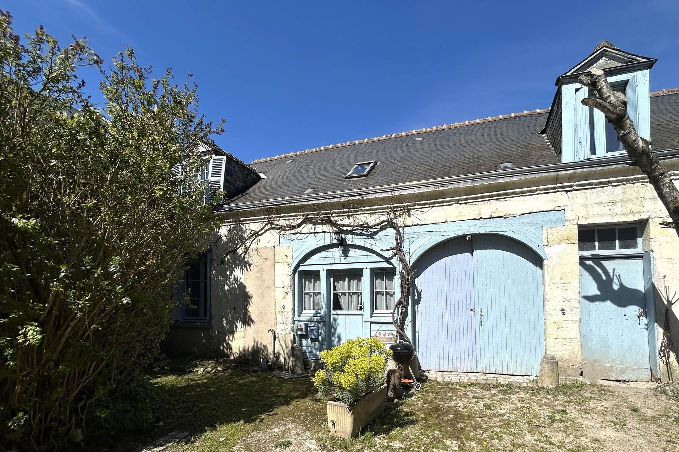 Un bâtiment traditionnel doté d’un toit en pente, de deux portes cintrées et d’une petite fenêtre.