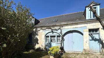 Un bâtiment traditionnel doté d’un toit en pente, de deux portes cintrées et d’une petite fenêtre.