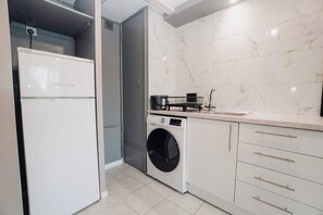 A compact kitchen with a washing machine, a sink, and a refrigerator. - Free Parking 2BR Sleeps 5 Close to JR Hospital (Headington)