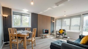 Ein modernes Wohnzimmer mit Essbereich, einer Couch und einem Fernseher.
