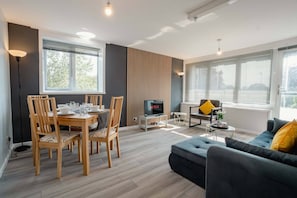 A modern living room with a dining area, a sofa, and a TV. - Free Parking 2BR Sleeps 5 Close to JR Hospital (Headington)