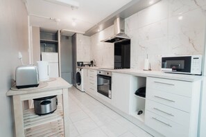 Eine moderne Küche mit Einbauofen, Mikrowelle und einer kleinen Essecke mit Toaster.